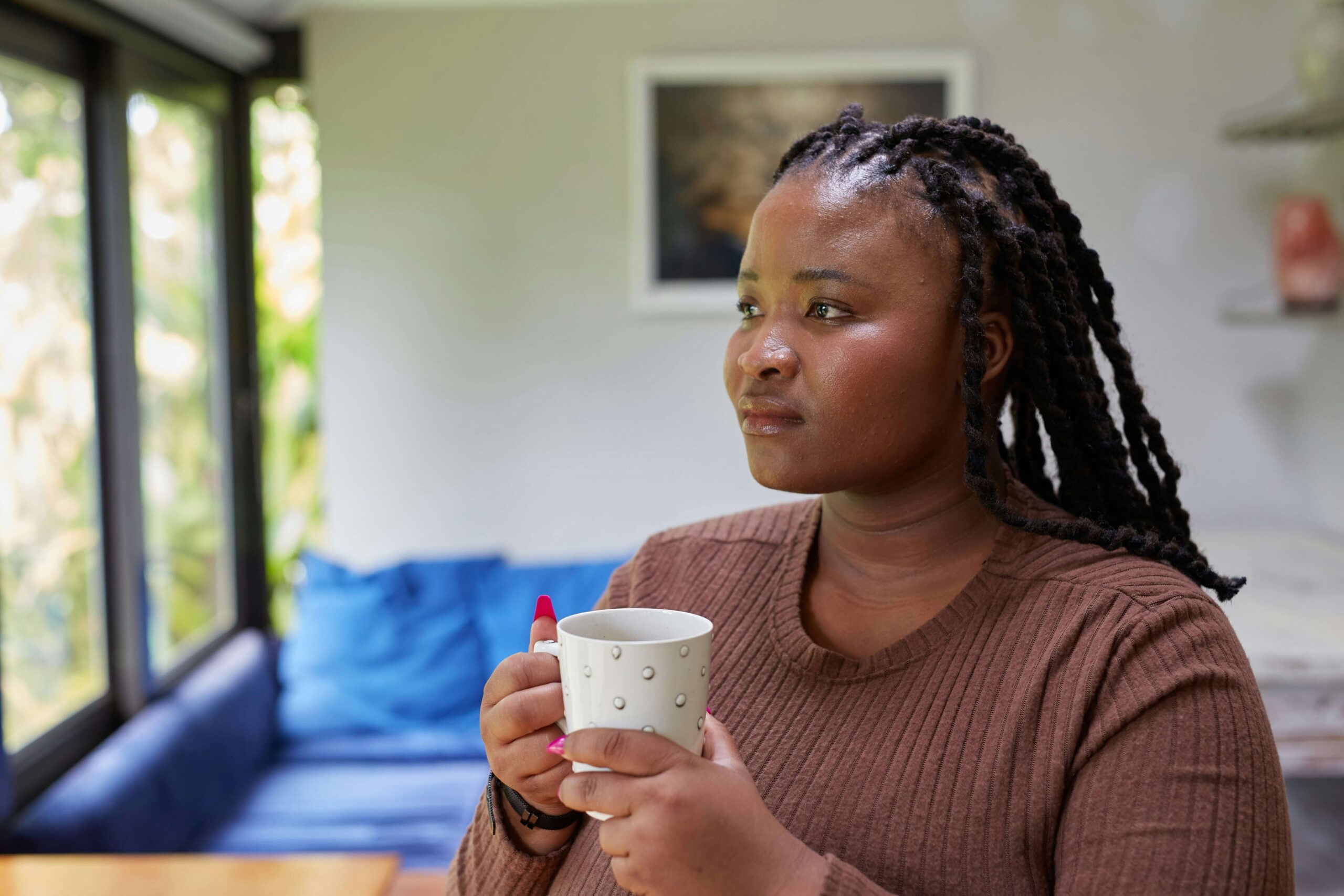 Woman holding a cup and looking thoughtfully out of a window